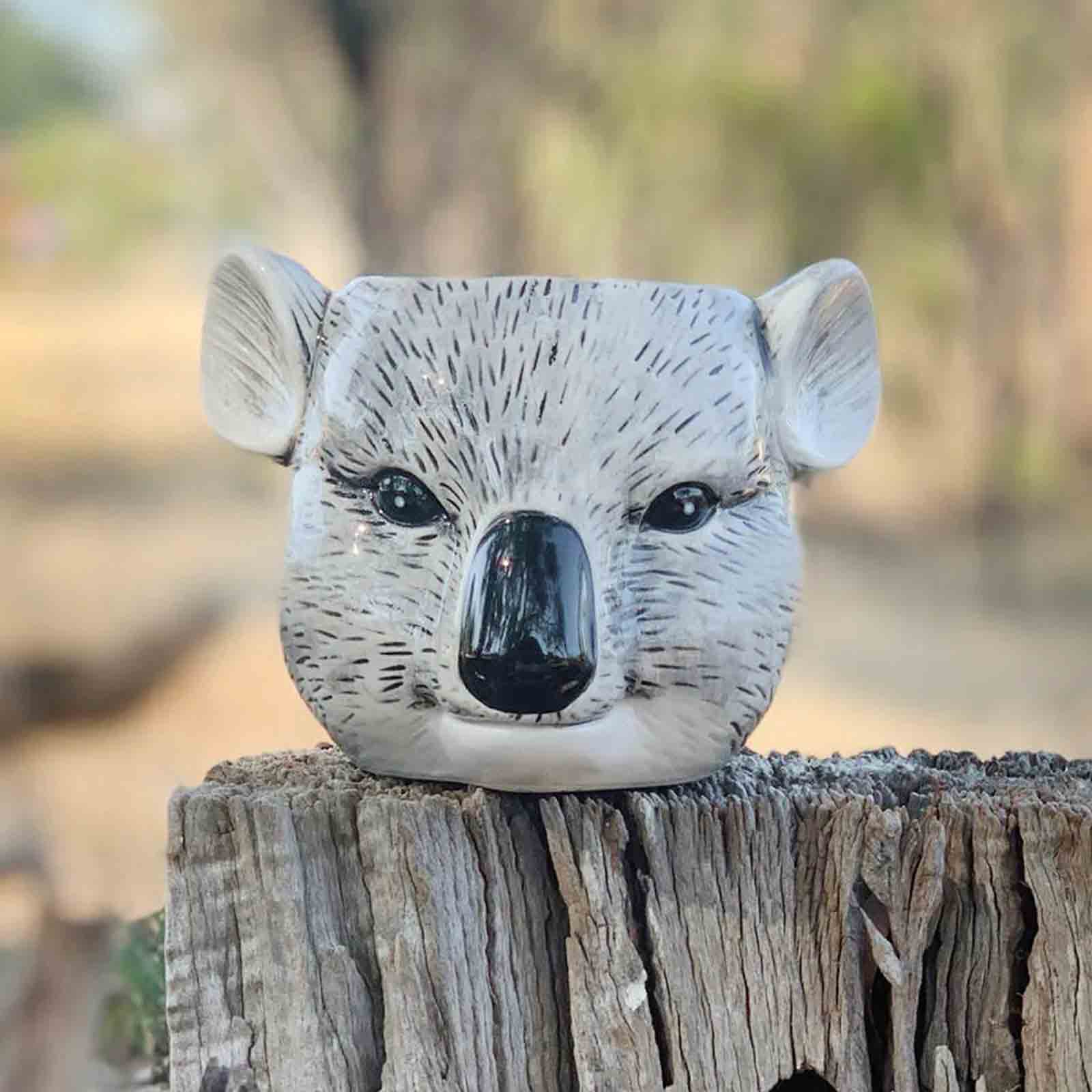 Decorative koala head planter / pen holder on a wooden post with a natural background