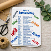 Tea towel with Australian slang words on a table with scissors and twine.