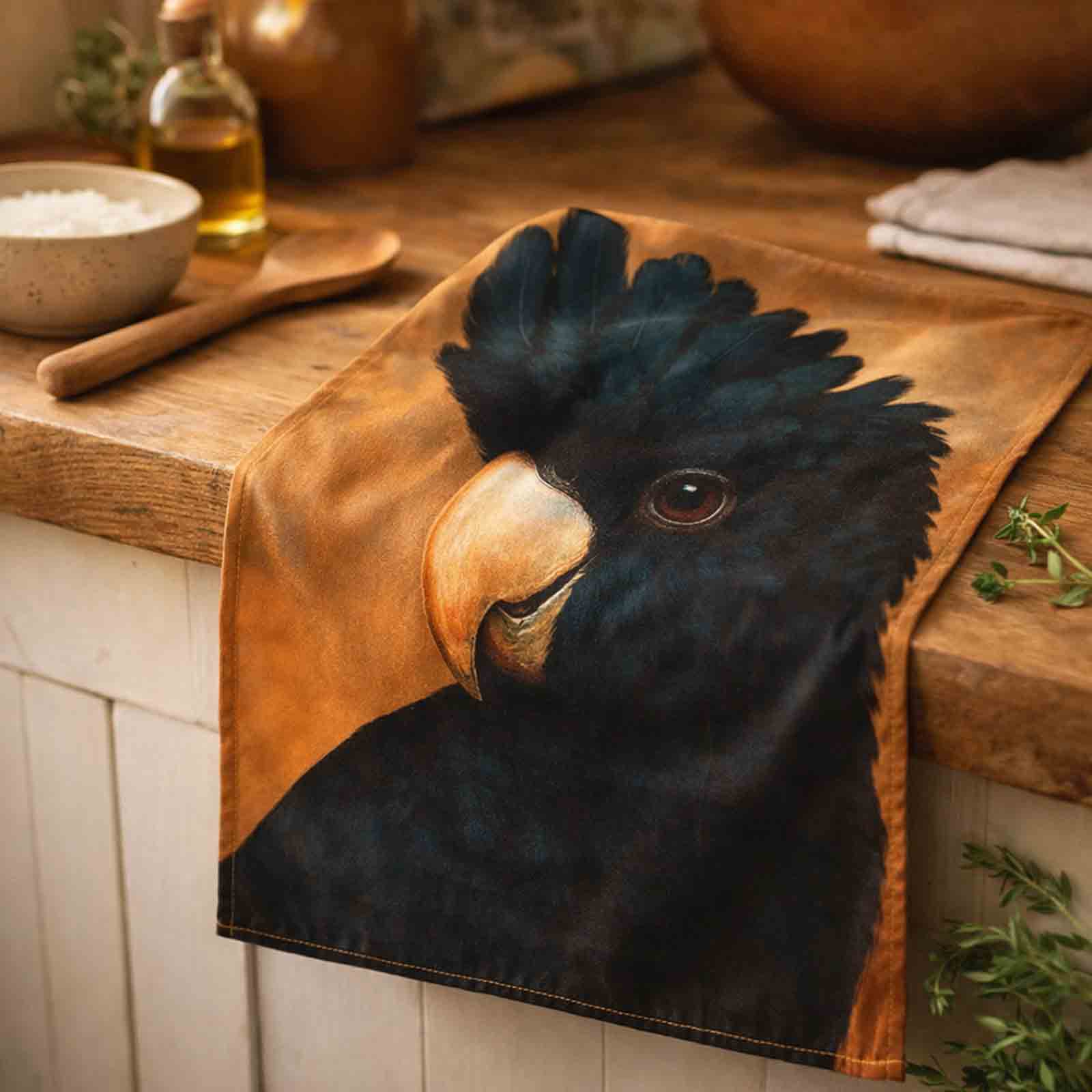 Kitchen tea towel with a Black Cockatoo design on a wooden surface
