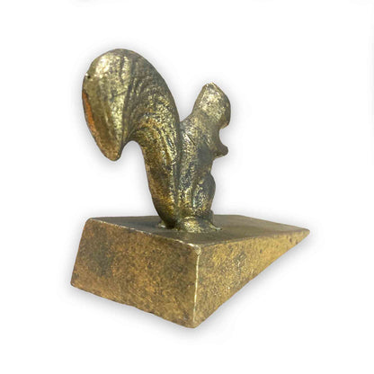 Gold coloured metal squirrel door stop wedge on a white background