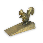 Gold coloured metal squirrel door stop wedge on a white background