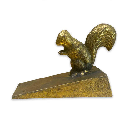 Gold coloured metal squirrel door stop wedge on a white background