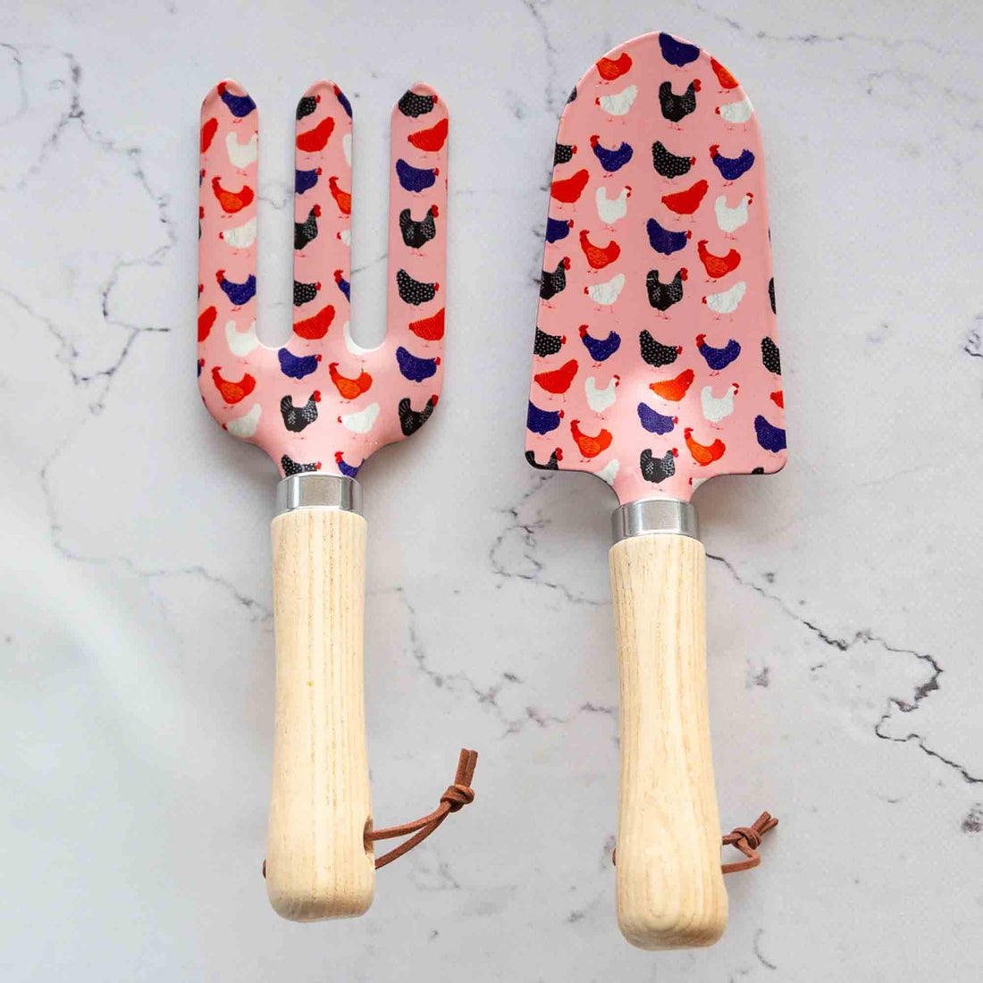 Set of gardening tools with a pattern of chickens on a bright pink coloured background.