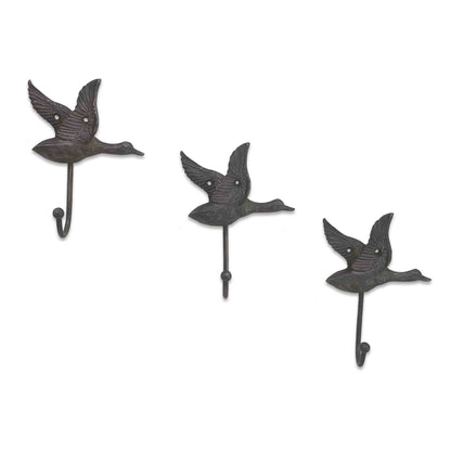 Three metal wall hooks shaped like ducks on a white background
