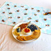 Platter of assorted snacks on a table with a bee-patterned tea towel.