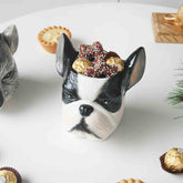 Dog-shaped candy dish with chocolates on a white surface