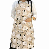 Woman wearing a greyish beige sheep apron with front pocket, cozy farmhouse‑style kitchen wear -Hello Homewares.