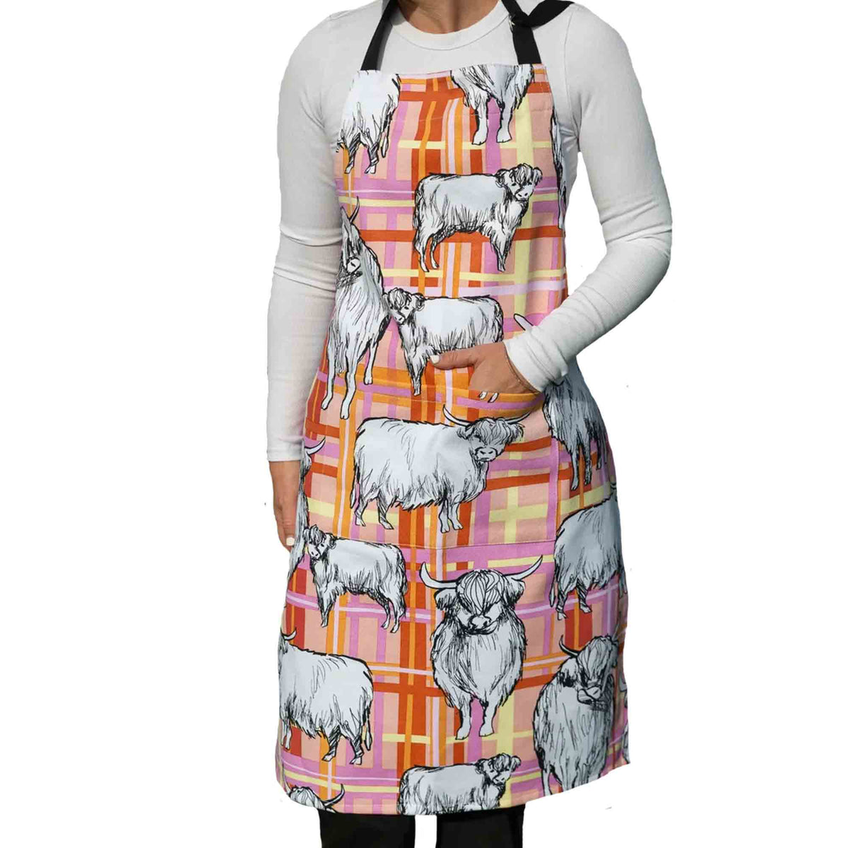 Highland Cows Heavy Drill Cotton Apron featuring a charming Highland cow print on a pink, orange and cream tartan background. Durable cotton kitchen apron with adjustable neck strap, ideal for cooking, baking, gardening, crafting and country-style farmhouse kitchens. Perfect gift for Highland cow lovers, home cooks and bakers.