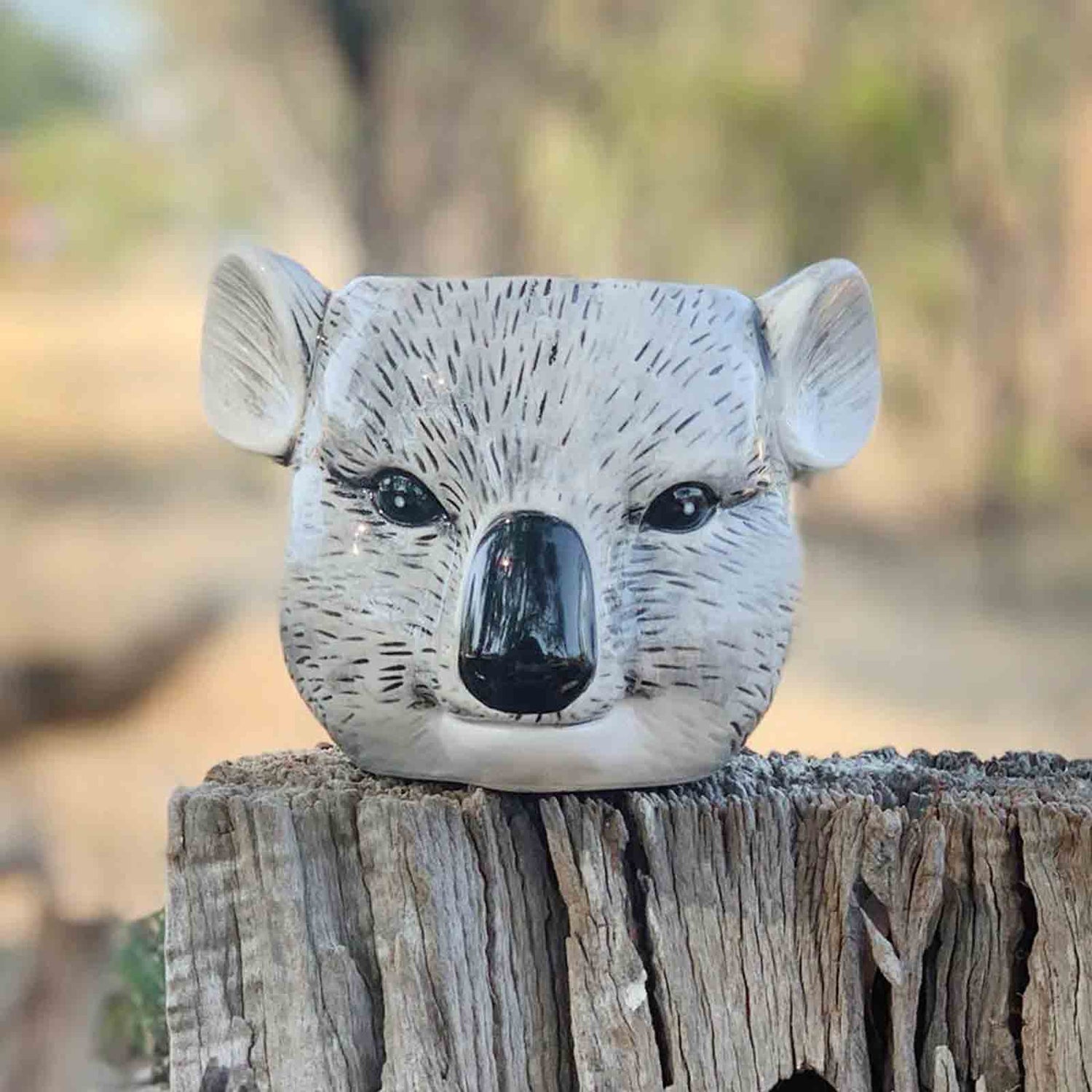 Decorative koala head planter / pen holder on a wooden post with a natural background