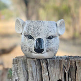 Decorative koala head planter / pen holder on a wooden post with a natural background