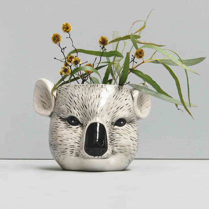 Ceramic koala planter with greenery on a light gray background