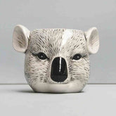 Ceramic pot shaped like a koala face on a plain background