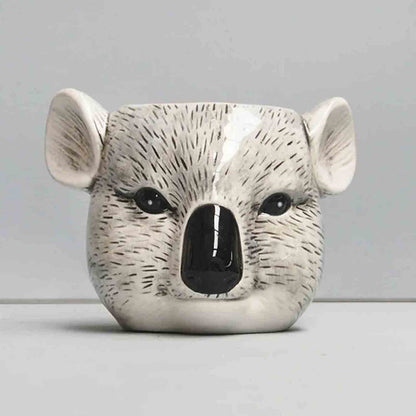 Ceramic pot shaped like a koala face on a plain background