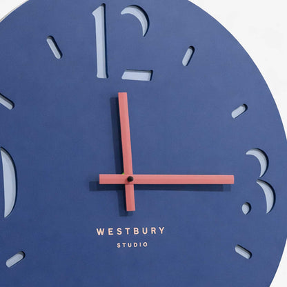 Close‑up of coral‑pink metal clock hands on deep blue wooden clock