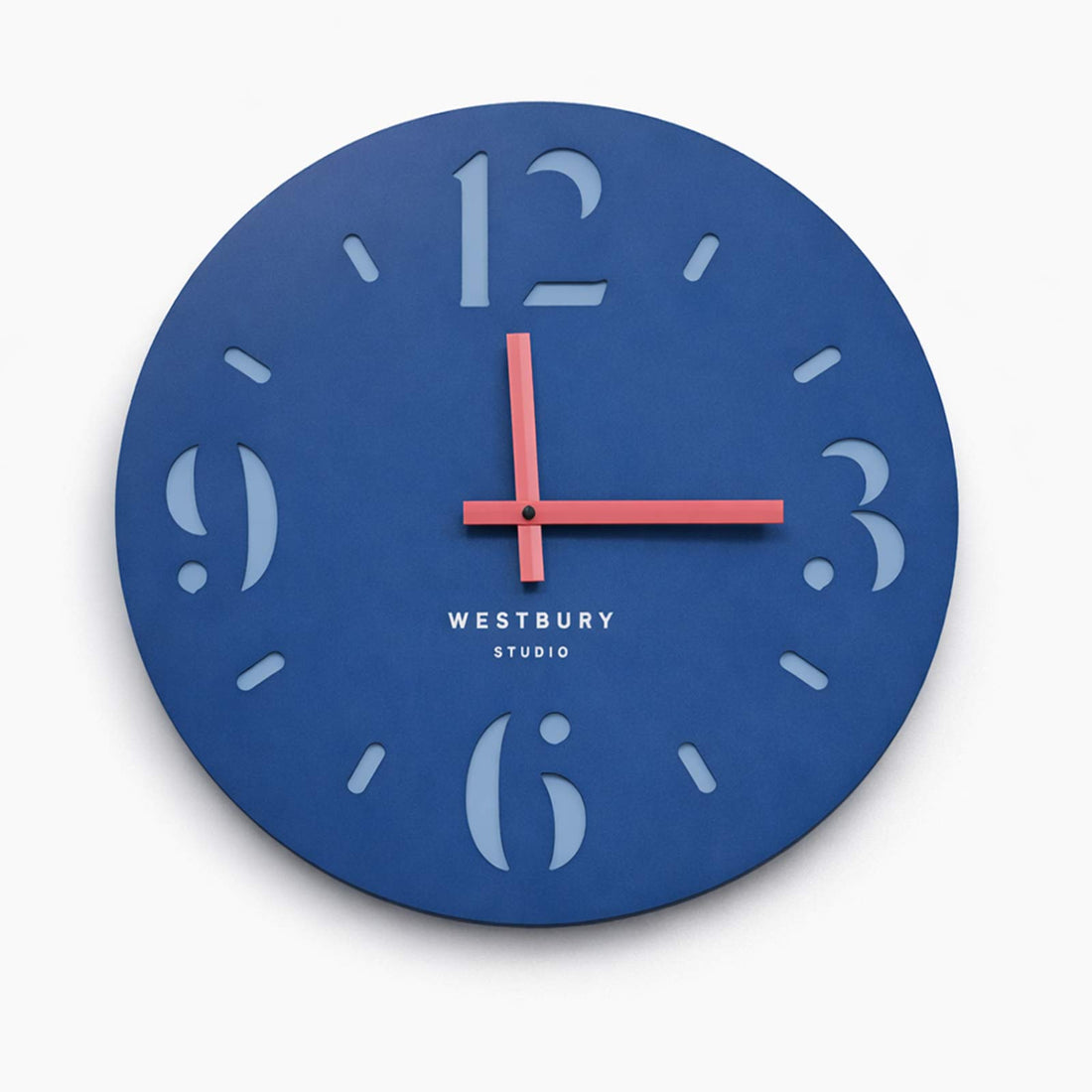 Blue 50cm Westbury Studio wall clock with coral‑pink hands on white background