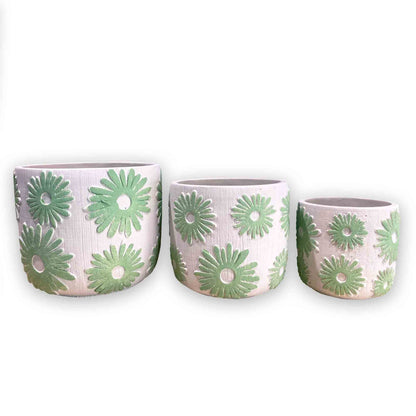 Three concrete planters with green floral daisy patterns on a white background
