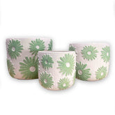 Set of three concrete planters with green floral daisy patterns on a white background