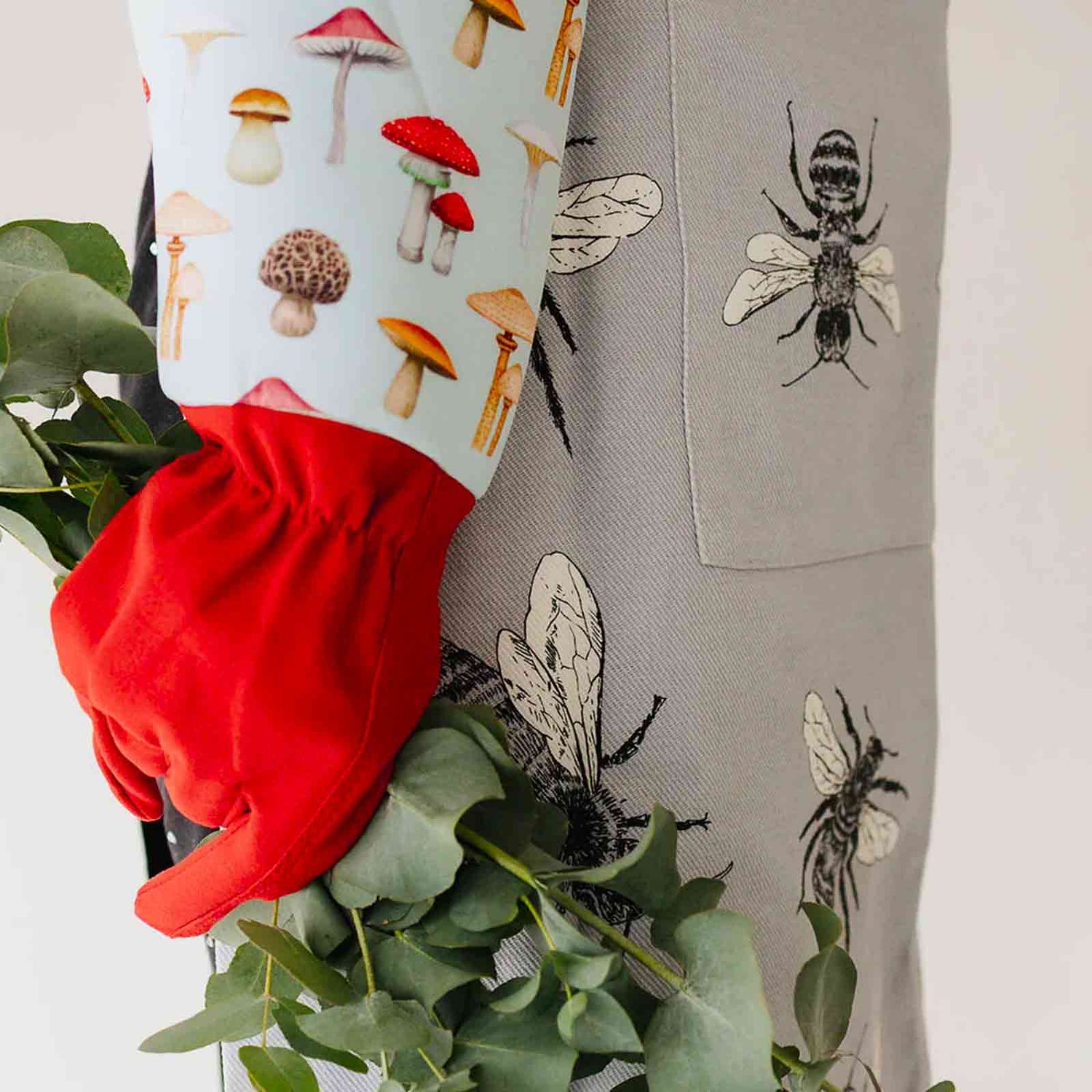 Woman wearing Mushroom Gardening gloves and a grey sketch bee apron