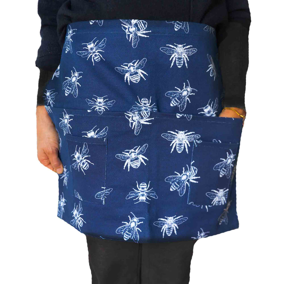 Blue apron with white bee pattern worn by a person on a white background