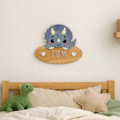 Customisable personalised dinosaur wooden door sign hanging on a wall above a bed with a dinosaur plush toy